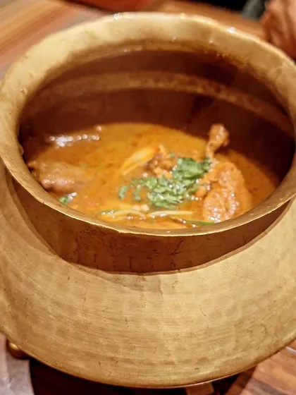 A traditional brass pot used for serving curries at Loya, adding to the authentic experience.
