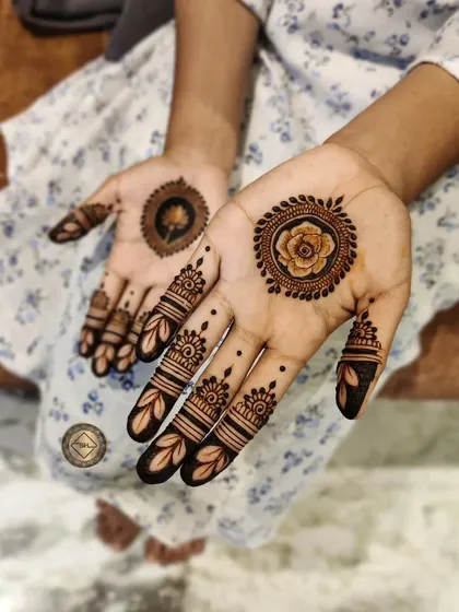 Love for florals. This simple party henna features a rose mandala on one palm and a different flower on the other, with delicate leaf patterns on the fingers.