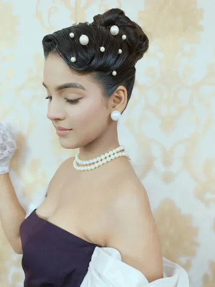 A side profile of the pearl-studded vintage updo. This angle showcases the sculpted waves and the careful placement of each pearl, highlighting the precision required for detailed period hairstyling.
