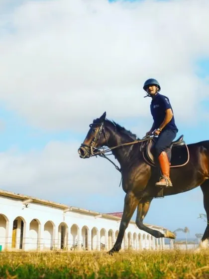A close up of a rider in motion, highlighting the focus and connection required to ride well, set against the backdrop of our stables.