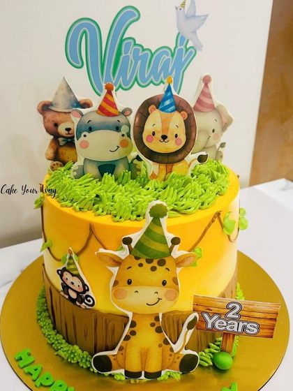 All the party animals are here to celebrate a second birthday. This jungle cake features a giraffe, lion, hippo, and more, all wearing party hats.