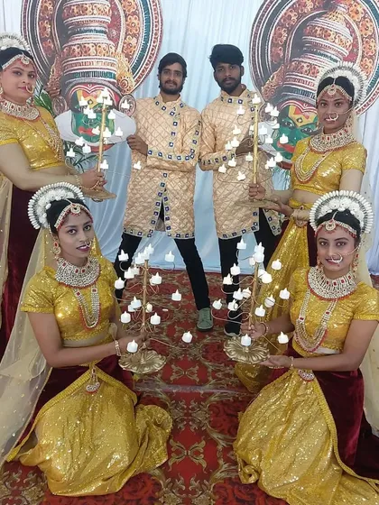 To add a cultural touch and a warm welcome for guests, I arrange for traditional performance troupes. Here, dancers in ornate costumes perform a welcome ceremony with lighted candelabras at a corporate event entrance.