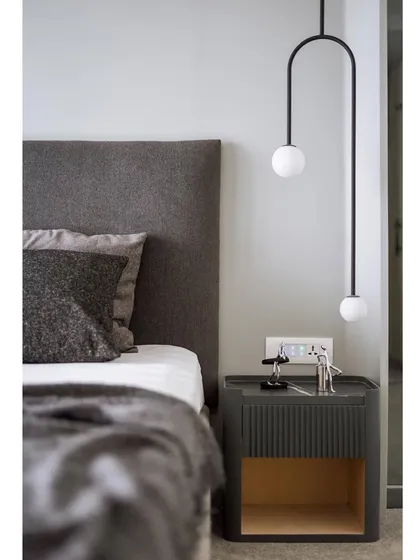 A close-up of the custom bedside table and suspended light. The fluted detail on the table and the simple geometry of the light fixture showcase our attention to craftsmanship and detail.