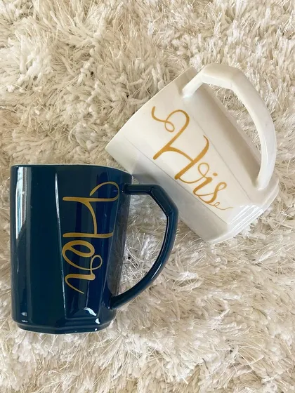 A top down view of the stylish "His" and "Hers" mug set, showing off the clean lines and elegant gold lettering. These are available to be added to any custom hamper.