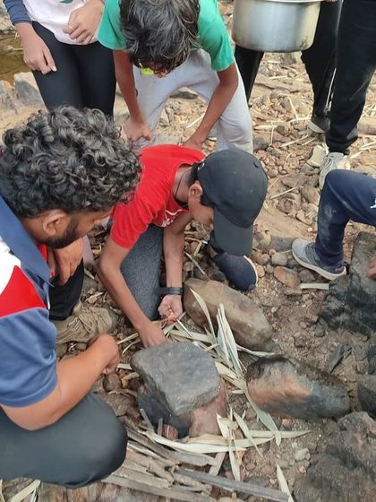 An instructor teaches campers how to prepare food using basic tools in the wild.