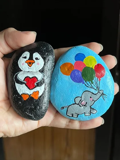 Even small items can become special keepsakes. Here are two examples of my stone paintings, featuring a cute penguin holding a heart and a baby elephant being lifted by balloons.