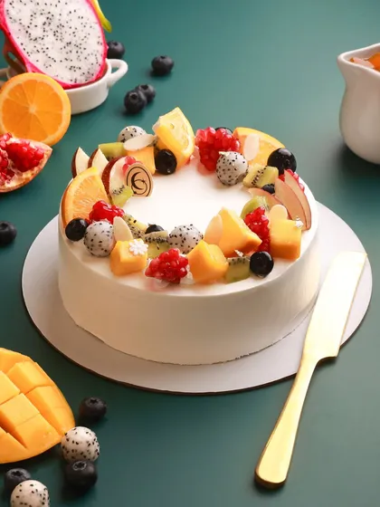 Our Summer Fruit Cake is a celebration of freshness. We layer light, fluffy cake with silky custard cream and top it with a vibrant assortment of seasonal fruits like mango, dragon fruit, and berries.