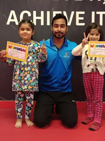 Double the pride. A coach poses with two young gymnasts who both earned their certificates.