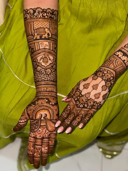 A beautiful bridal design featuring asymmetrical patterns on each hand, one with a grid and the other with flowing paisleys, tied together with elephant and bell motifs.