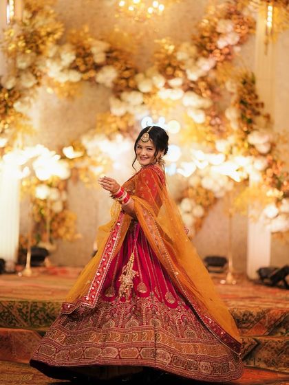 A full-length portrait of the bride, Proneeta, twirling in her gorgeous red and yellow lehenga. This shot captures the grandeur of her outfit and her joyful spirit.