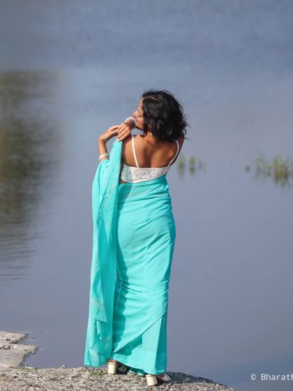 Another beautiful shot from the back, this portrait emphasizes the elegant drape of the saree and the peaceful waterside setting.