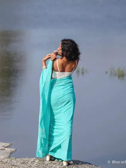 A back view of the model in the turquoise saree, looking over her shoulder. This shot emphasizes the simplicity and elegance of the look.