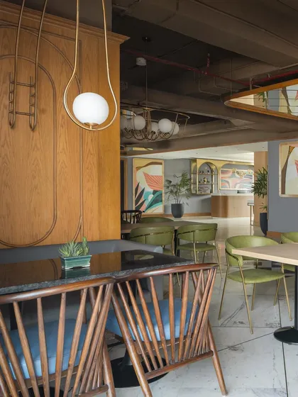 A view across the Citadines restaurant shows the layered design. In the foreground, mid-century style wooden chairs create a relaxed feel, while the background offers a glimpse of the more formal lounge and bar areas.