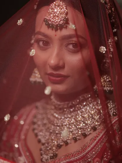 A captivating shot of my bride Krupa through her red veil. Her look features soft, sculpted skin, a flush of rose, and bold eyes for a timeless bridal glow.