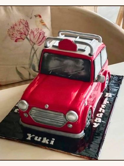 A sculpted 3D cake of a red Mini Cooper car, showcasing detailed craftsmanship for a car enthusiast's birthday.
