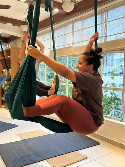 A student gracefully holds a pose in the aerial hammock, showcasing the elegance and strength that this practice cultivates.