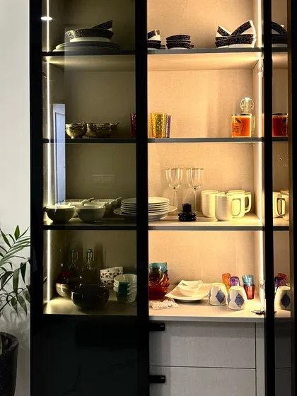 The fully stocked crockery unit showcases its generous storage capacity. The combination of glass shelves for delicate items and solid bases for heavier sets makes it a highly practical piece of dining room furniture.