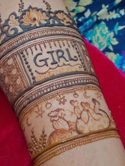 A close-up of the arm detail from the baby shower design. It shows the word 'GIRL' with a cute drawing of a stork carrying a baby, surrounded by stars and the moon.