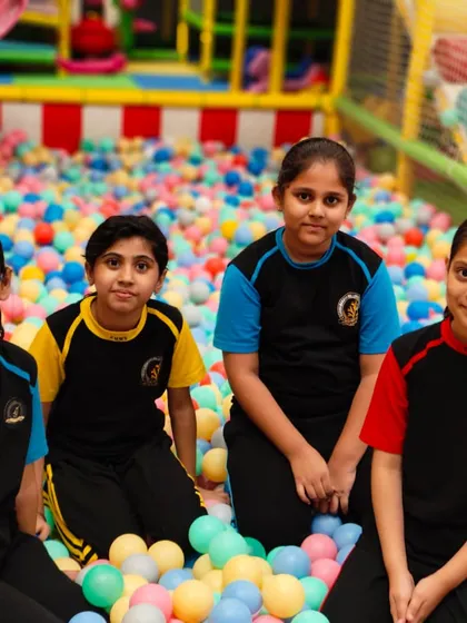 A group of friends posing for a photo in the ball pit during their school outing.