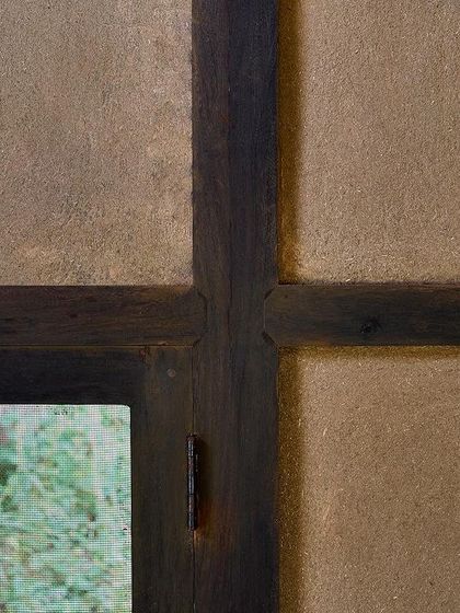 A close-up of the wattle-and-daub wall panel, showing the beautiful texture of the earth plaster and the precision of the wooden joinery.