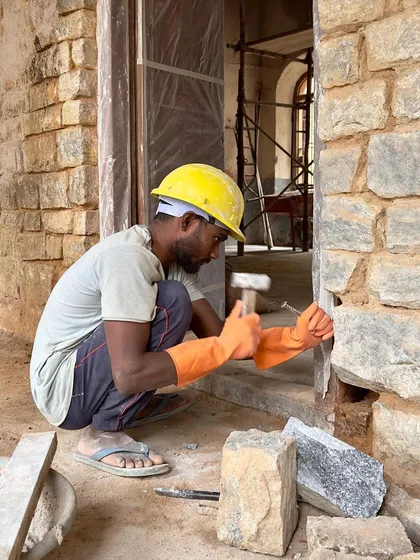 The hands of a master craftsman are essential to our work. Here, a stone mason carefully chisels a new piece for the restoration of a historic school. We collaborate closely with local artisans, reviving traditional techniques to ensure the authenticity and integrity of every heritage conservation project.