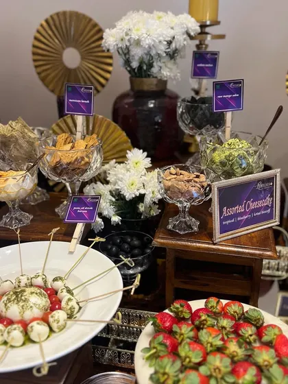 An elegant grazing table setup with a focus on presentation, using crystal bowls, gold accents, and fresh flowers to elevate the display of strawberries, cheeses, and dips.