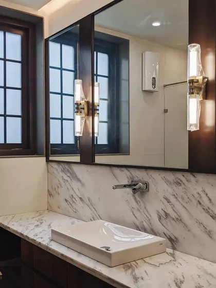 A preview of a bathroom interior, showcasing a marble countertop, a contemporary vessel sink, and elegant wall sconces that cast a warm, inviting light.