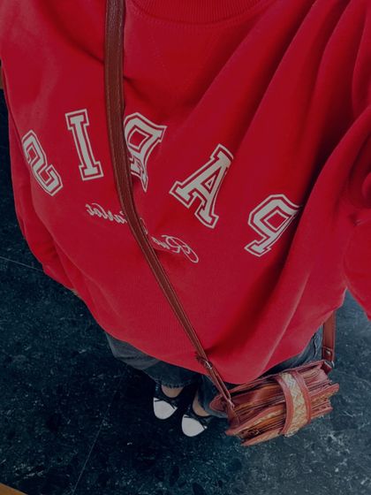 A cozy and casual outfit detail shot. A bright red GAP sweatshirt paired with dark jeans is a classic, comfortable combination for a laid-back day.