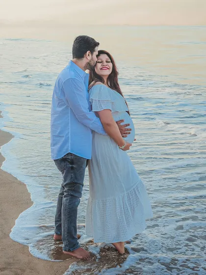 An outdoor maternity photoshoot at the beach, capturing a quiet moment between the expecting couple. The soft evening light and gentle waves create a serene and romantic backdrop for your pregnancy portraits.