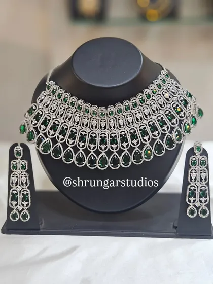 For the modern bride who loves to sparkle, this American Diamond necklace set is a showstopper. The silver-plated design is studded with high-quality AD stones and vibrant green gems, perfect for your sangeet, reception, or cocktail party. It gives you the look of real diamonds without the hefty price tag.
