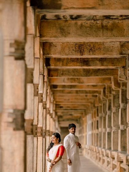 A beautifully composed shot using the repeating pillars of a temple corridor to create leading lines and frame the couple. This is a great example of architectural couple photography.