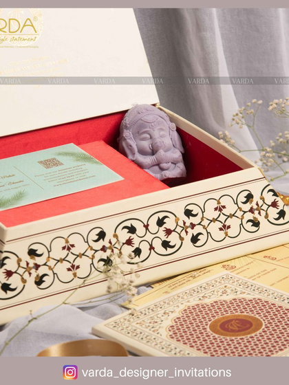 This keepsake box features a beautiful floral inlay pattern and a small Ganesha soap carving. It's paired with a set of traditional wedding cards, blending classic motifs with a touch of modern artistry.