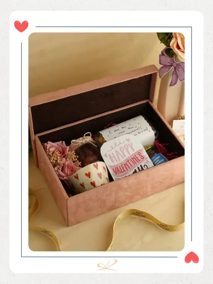 A lovely Valentine's hamper in a pink velvet box. It includes a heart-themed mug and other curated items, making it a soft and romantic gift.