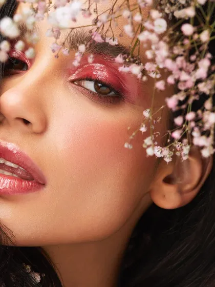 A glossy, pink-toned makeup look that is soft and romantic, beautifully framed by delicate baby's breath.