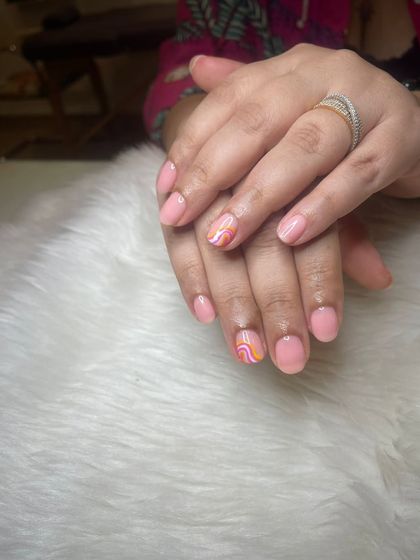 A recap photo showing a simple pink manicure with a colorful abstract swirl accent nail.