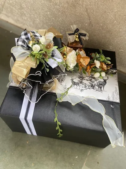 A winter-themed gift box with a classic black and white design. Adorned with a checkered bow and rustic floral accents, this hamper is perfect for holiday gifting or a cozy winter celebration.