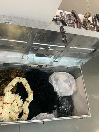 A trunk filled with wigs and garlands, part of the interactive props for visitors.