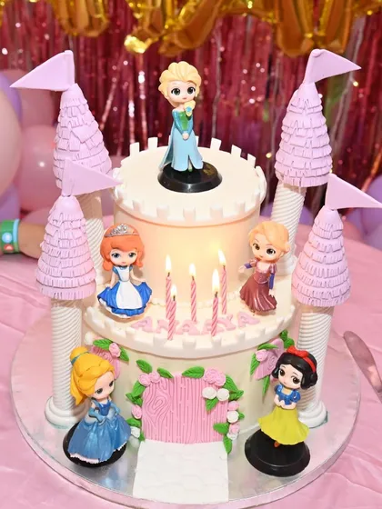 Another view of the enchanting Disney princess castle cake, lit with candles and ready for a birthday wish.