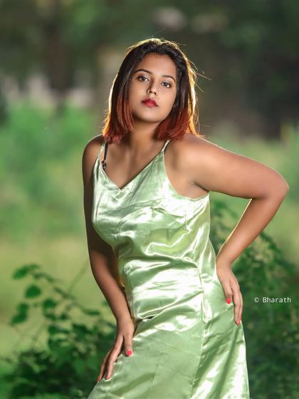 A classic editorial pose in a beautiful outdoor location. The soft green background makes the subject the clear focus.