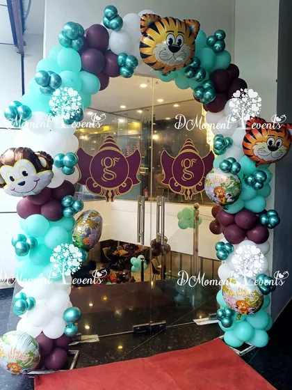 The entrance to the jungle party, featuring an arch of teal, white, and brown balloons accented with fun animal-themed foil balloons.