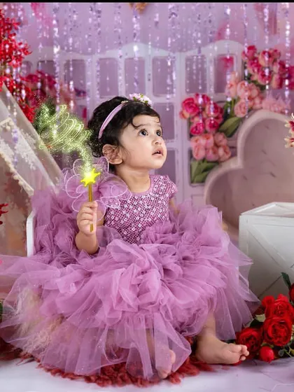 A fairy princess in her magical garden. The sparkling lights and floral props create an enchanting atmosphere for this toddler portrait session.