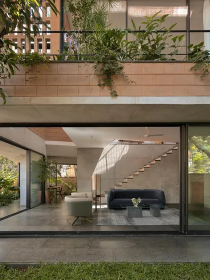 (Hero Media) This is our Debris Block House in Bangalore, where the ground floor opens completely to the landscape. We designed this to maximize the connection to the garden, with light streaming in from skylights and the multi-level open staircase, creating a seamless indoor-outdoor living experience.