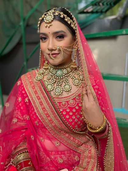 This bride looks lovely in a bright pink lehenga with gold embroidery. She paired it with one of our popular green-beaded Kundan sets for a beautiful contrast.