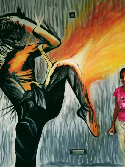 Here I am with a finished gym graffiti mural. The fiery, energetic figure was created with spray paint to inspire movement and power. It's about 20 feet wide and 11 feet high.