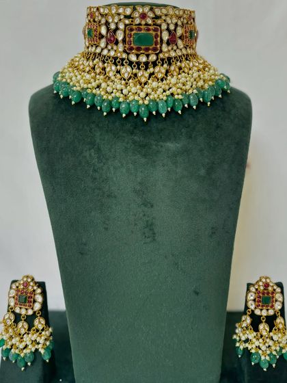 A Kundan and pearl choker with a border of green beads. This rental set includes small, matching earrings.
