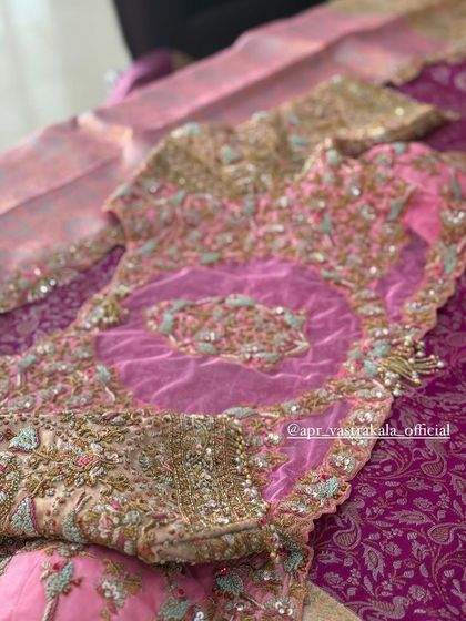 A pink blouse with delicate bird and floral embroidery, featuring a sheer back panel.