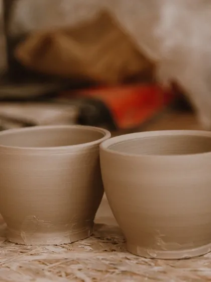 Two perfectly thrown, identical raw clay cups. This shows great progress and control on the pottery wheel.