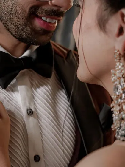 A detail-oriented shot focusing on the couple's style. This close-up highlights the groom's sharp tuxedo, the bride's stunning earrings, and the delicate way she holds his lapel.