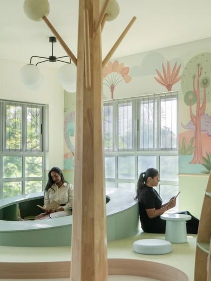 The flowing, curved lines of the built-in seating and the tree-like structures create a natural, organic feel in the nursery library. The space is bathed in natural light, making it a cheerful place to learn and play.