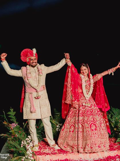 Triumphant and joyful! The couple raises their hands in celebration after their Varmala exchange, their happiness shared with everyone present.